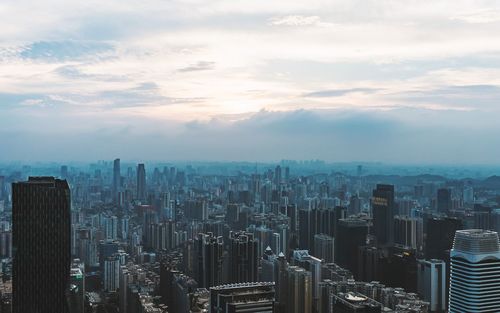 Aerial view of cityscape against cloudy sky