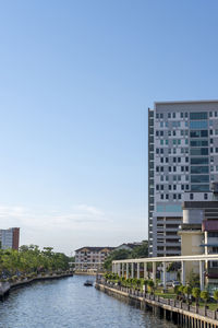 River amidst buildings against clear blue sky