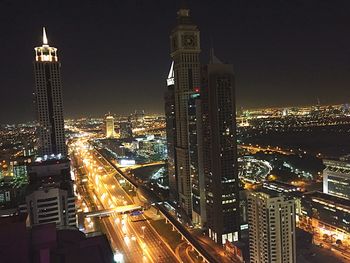 Illuminated modern buildings in city against sky at night