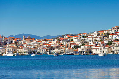 Townscape by sea against clear blue sky