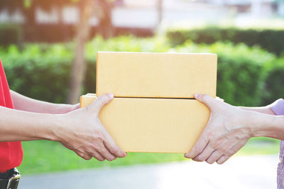 Midsection of people holding paper outdoors