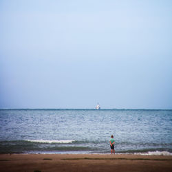 Boy at beach by sea against clear sky