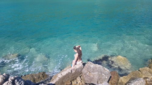 High angle view of woman standing on rock by sea