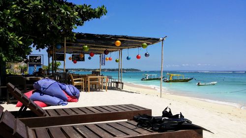 Lounge chairs on beach against clear sky