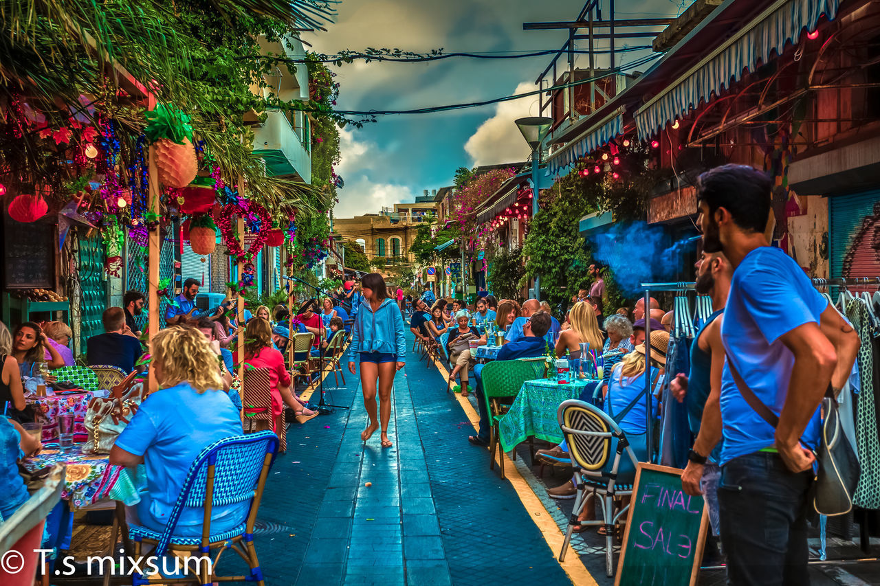 PEOPLE ON MULTI COLORED UMBRELLAS AGAINST SKY