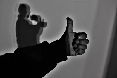 Man standing by shadow gesturing thumbs up at home