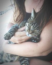 Midsection of mature woman holding cat while sitting outdoors