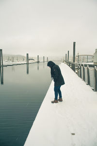 Full length of man standing on pier against sky during winter