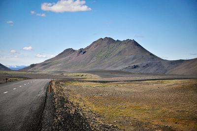 Scenic view of road and mountains against blue sky