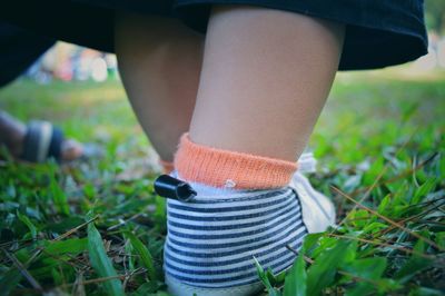 Low section of baby wearing shoes on grass