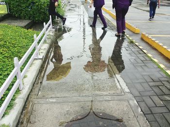 Low section of people walking on wet puddle