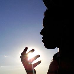 Low angle view of cropped hand holding camera against sky