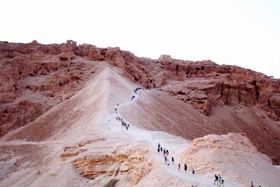 High angle view of people hiking on mountain against clear sky