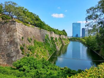 Scenic view of river by buildings against sky