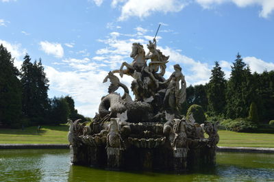 Statue by lake against sky