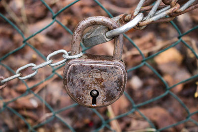 Close-up of rusty chain with padlock on chainlink fence