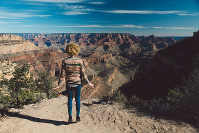 Rear view of woman walking on landscape against sky