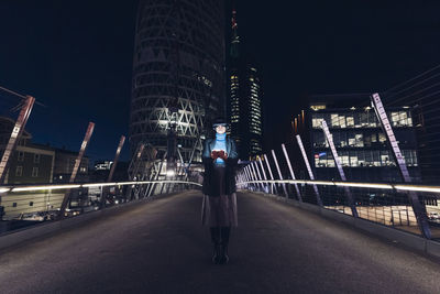 Businesswoman with virtual reality headset standing on bridge in city