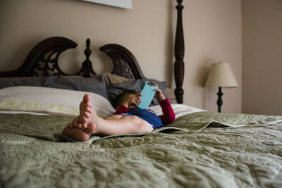 Boy using mobile phone while lying on bed at home