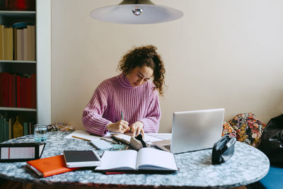 Young woman doing homework at table