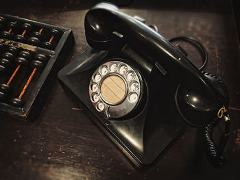 High angle view of old telephone with abacus on table