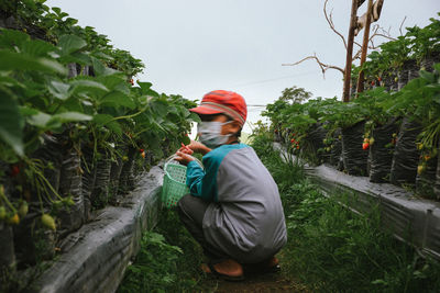 Side view of young woman standing against trees