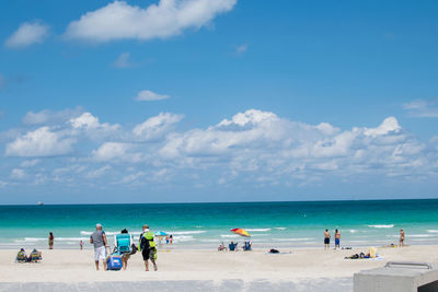 People at beach against blue sky