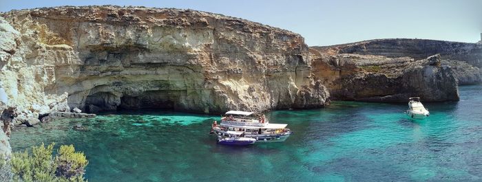 Boat sailing on sea by cliff