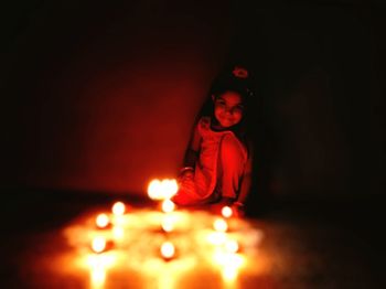 Smiling girl looking at illuminated decoration in darkroom