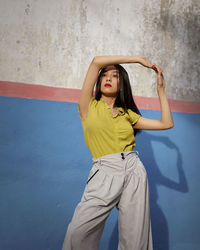 Portrait of woman standing against wall