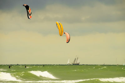 Person paragliding flying over sea against sky