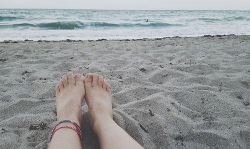 Low section of woman on beach against sky