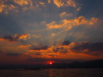 Scenic view of sea against dramatic sky during sunset