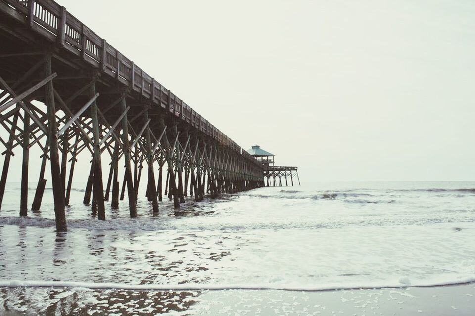 sea, water, clear sky, horizon over water, beach, pier, copy space, tranquil scene, tranquility, built structure, shore, scenics, nature, railing, beauty in nature, sky, in a row, architecture, day, sand