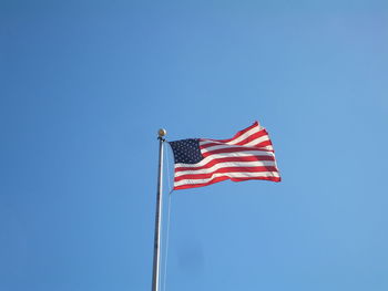 Low angle view of american flag against clear blue sky