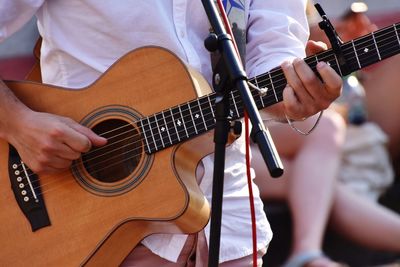 Midsection of artist playing guitar while performing at music concert