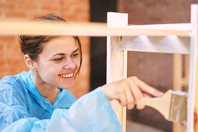 Portrait of smiling young woman standing by window