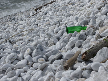 Garbage on the beach . particular of a green bottle abandoned between the pebbles