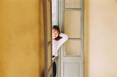 Portrait of smiling young woman against door