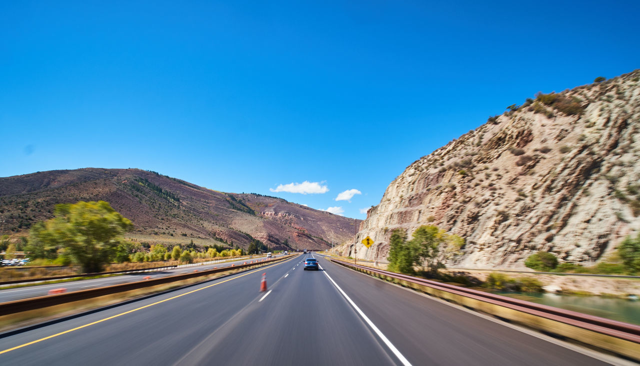 ROAD PASSING THROUGH MOUNTAIN AGAINST BLUE SKY