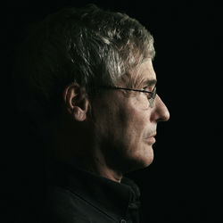 Side view of man wearing eyeglasses against black background