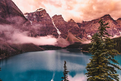 Scenic view of lake by mountains against sky during sunset