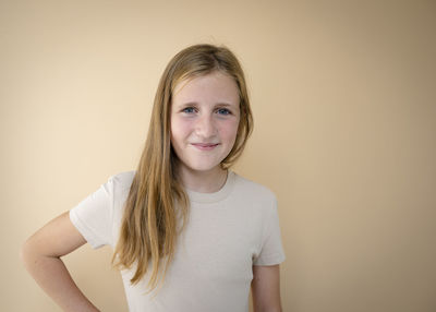 Portrait of young woman standing against wall