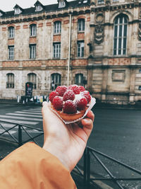 Midsection of person holding ice cream in city