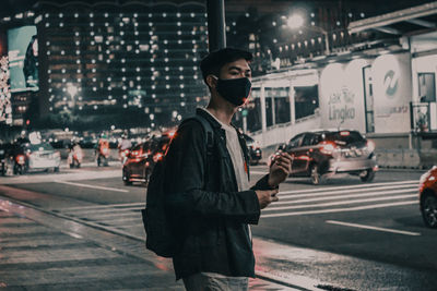 Side view of young man standing on city street