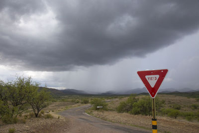 Road passing through mountains against cloudy sky