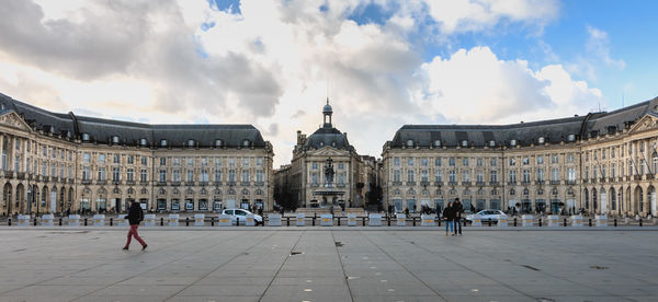 People at historic building in city against sky