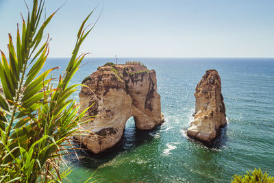 Rock formation in sea against clear sky