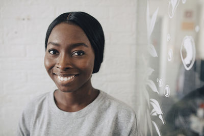 Portrait of confident creative businesswoman against wall in office