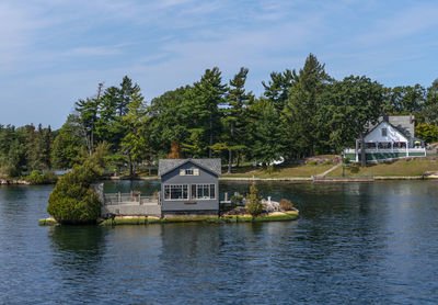 House by lake and building against sky